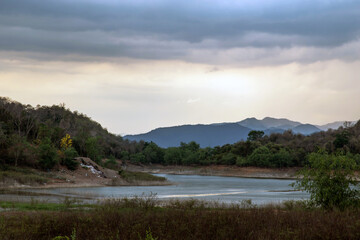 View of lake shore with mountains range in background at sunrise or sunset. No focus, specifically.