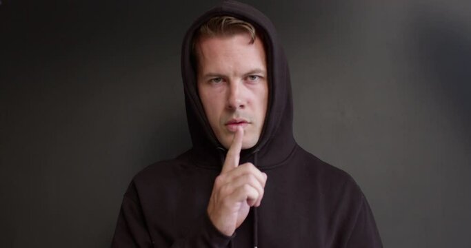 Man burglar pedophile kidnapped someone, holds hostage, ask to be quiet, asks for ransom for kidnapped person, posing isolated over black studio background. adult man pedophile in black wear