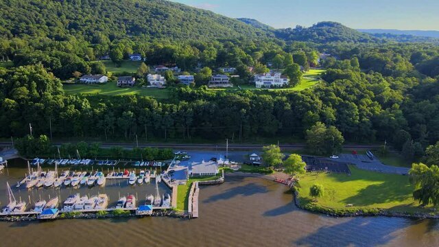 Aerial drone footage of the Cornwall on Hudson waterfront during summer as seen from the Hudson river, with the Appalachian mountains in the background. 