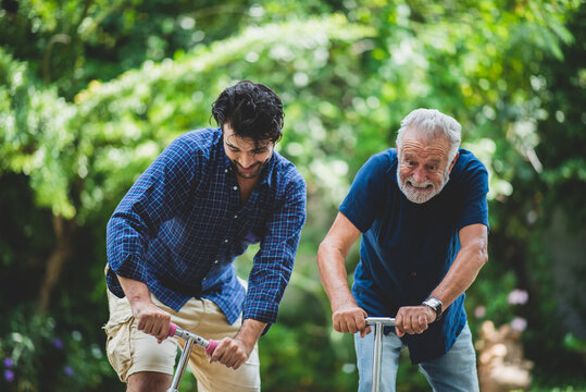 senior father and hipster adult son are happy love and relaxing together at nature outdoor park, mature family of elderly caucasian beard man playing fun with family in retirement leisure time