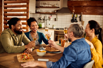 Cheerful multi-ethnic people toast with champagne at dining table.