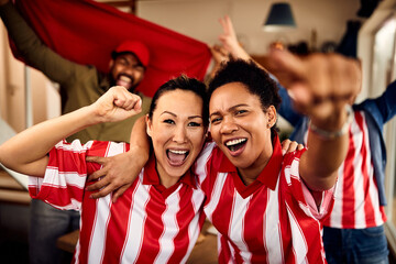 Cheerful group of fans cheer and have fun while watching sports game at home.