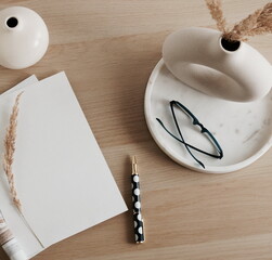 Home desk workspace with magazin blank mockup copy space. Modern vase on marble tray, glasses, pen...