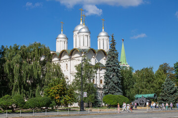 Fototapeta na wymiar the white-stone Cathedral of the Twelve Apostles among the green foliage of trees in the Kremlin on Cathedral Square on a sunny summer day and cloudy blue sky in Moscow Russia