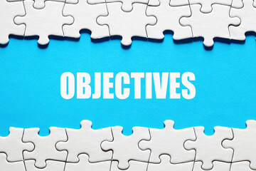 The word objectives framed by jigsaw puzzle pieces. To discover or set business or company...