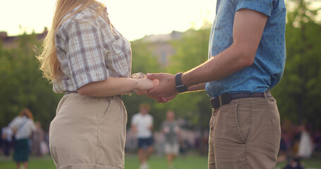 Fototapeta na wymiar Cropped shot of young caucasian couple holding hands in summer park