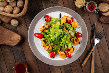 Salad with lettuce and fried chicken on wooden background