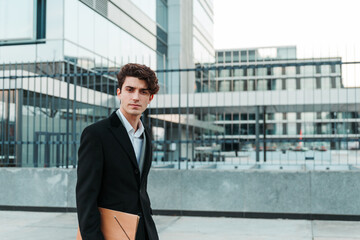 young man in casual suit with notebook in hand walking