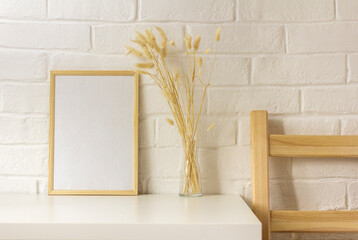 An empty photo frame and dried flowers in a vase on the table with a copy of the space.Scandinavian style.