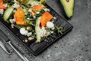 Fresh salad with fruits and greens on dark canvas background. Healthy food