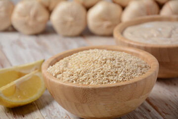 Wooden bowl and spoon with white sesame seeds on vintage wooden background