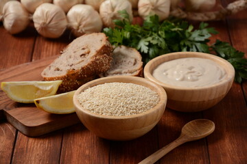 Wooden bowl and spoon with white sesame seeds on vintage wooden background