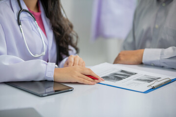 Asian women Doctor and man patient discussion about  result x-ray images in clinic office