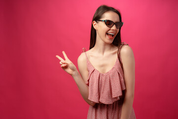 Young casual brunette woman in sunglasses against pink background