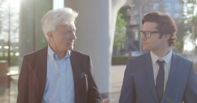 Medium shot of happy business colleagues having conversation walking outside.