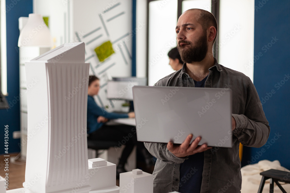 Poster professional man working as architect at office while using laptop computer for blueprint design. ad
