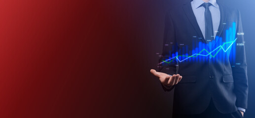 Business man holding holographic graphs and stock market statistics gain profits. Concept of growth planning and business strategy. Display of good economy form digital screen.