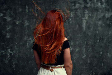 Rear portrait of a redhead model with curly hair on a gray background. - 449131266