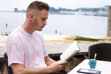 young man reading a book outdoors