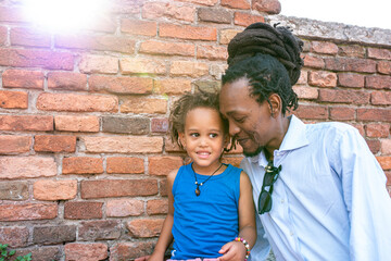 father and son in moment of tenderness, mixed African Caucasian family, flare effect of the sun,...