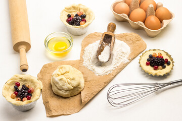Flour and dough on paper. Baking cup with frozen berries and dough.