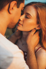 Naklejka premium Close up photo of a caucasian ginger woman with freckles kissing and embracing in the sunshine