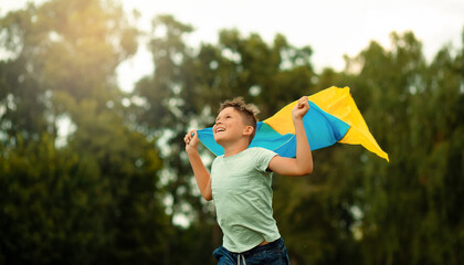 Happy ukrainian boy running with wawing yellow and blue national flag Love Ukraine concept. Independence, flag, constitution day of Ukraine