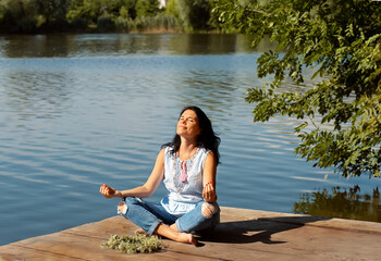 Naklejka na ściany i meble Woman Yoga - relax in nature. sitting on pier lake