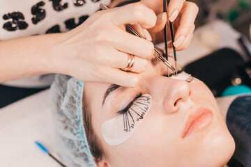 Close-up of the work of a beauty beautician on eyelash extension with artificial bundles