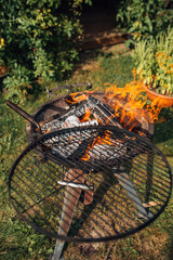 Round steel barbecue grill with rotating grate wood flame - resting in the backyard