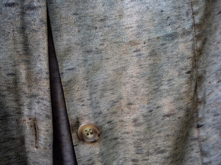 detail of the fabric of a shabby shirt with the button and the hole