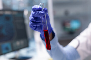 Doctor researcher holding blood test tube in hands working at microbiology experiment in clinical biotechnology hospital laboratory. Chemist analyzing virus expertise discovering biology infection