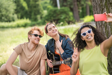 Friends taking selfie on smartphone at picnic