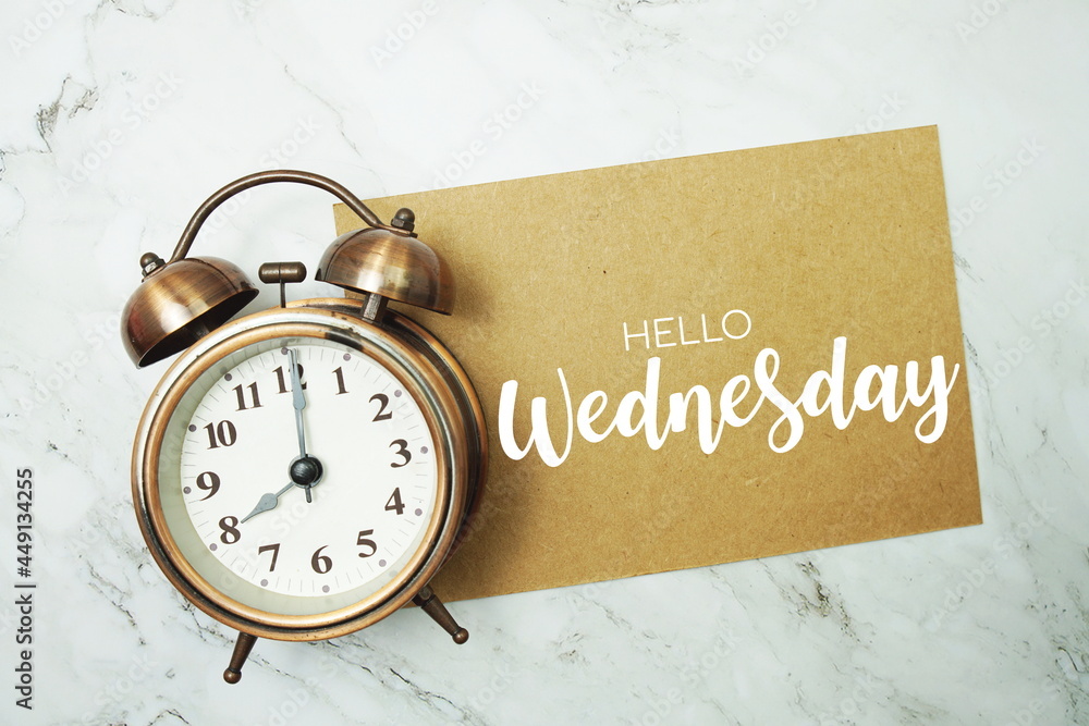 Poster hello wednesday typography text on paper card with alarm clock on marble background