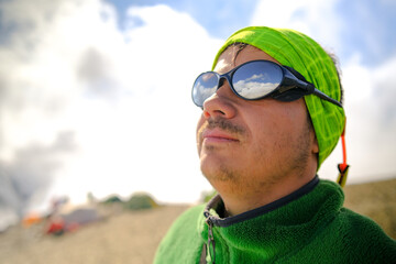 Portrait of a slightly unshaven man in mountain sunglasses.