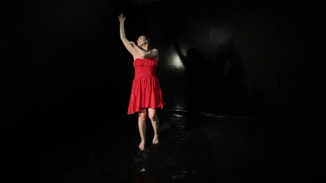 Woman in a red dress is dancing in the water contemporary.