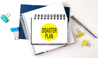 Sticker with DISASTER PLAN text on notebooks on the white background