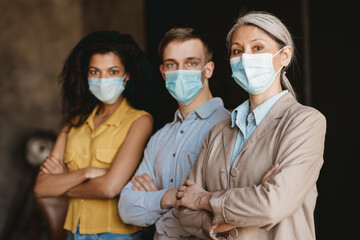 Man and women in face mask looking at camera while standing by wall