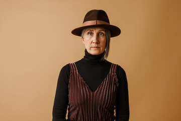 Grey senior woman in hat posing and looking at camera