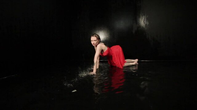 Woman in a red dress is showing a show, she is dancing in the water.