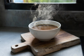 Steam of hot soup with smoke wood bowl on old  kitchen background.selective focus.hot food concept