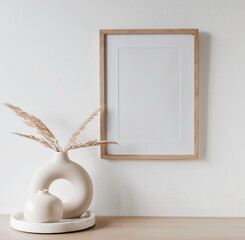 Fototapeta na wymiar frame mockup on beige table, modern beige ceramic vases on tray with dry grass.Neutral color. White wall background. Scandinavian interior. Copy space.