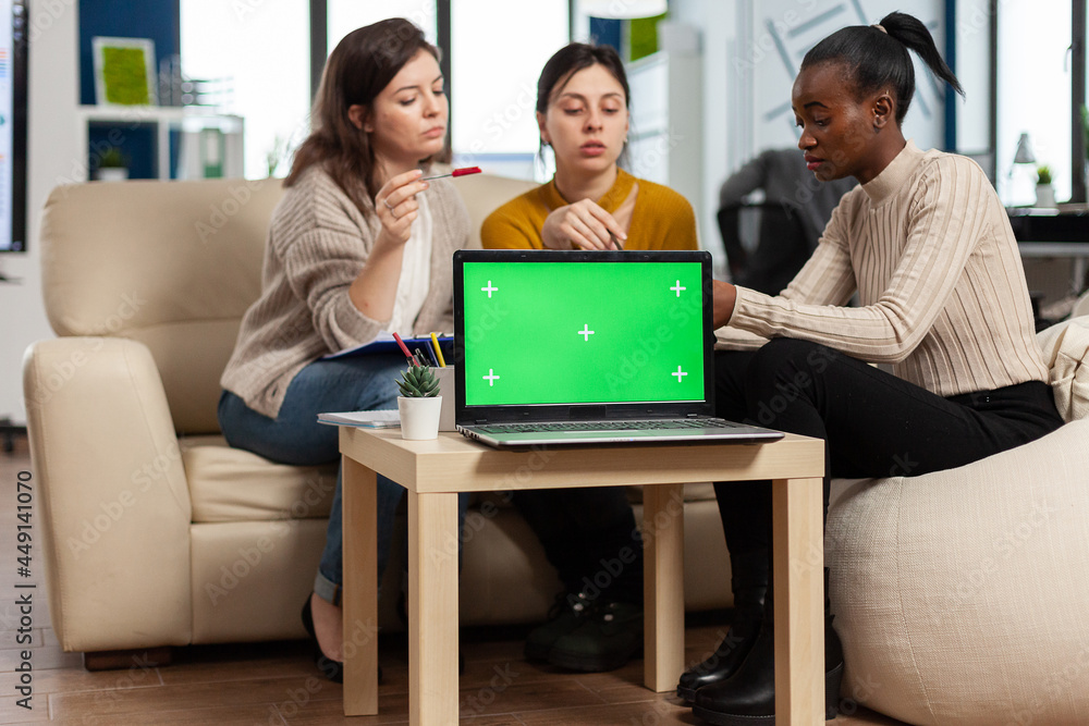 Poster laptop with chroma key display on table in startup business workplace. african manager discussing ta