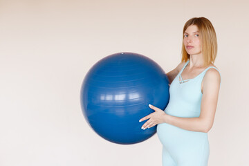 pregnant woman in blue jumpsuit with fitness ball in training