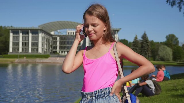 Portrait of preteen schoolgirl talk on mobile phone standing in school park