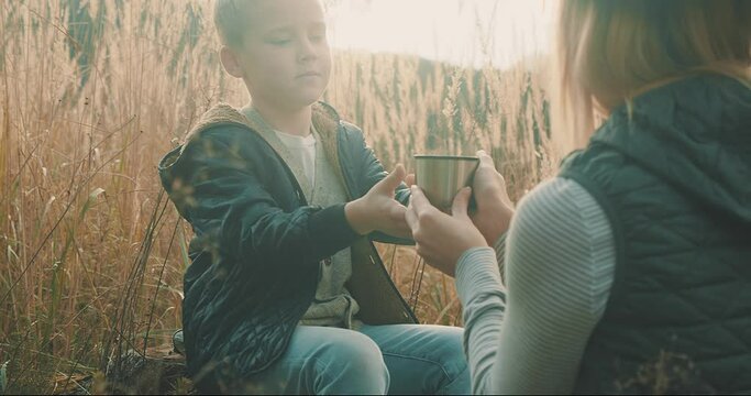 Happy Mother And Son Hiking Traveler Camper Drinking Hot Tea And Relaxing In Fall Forest On Sunny Autumn Day. Beautiful Mountain Landscape View. 4K Slow Motion Video.