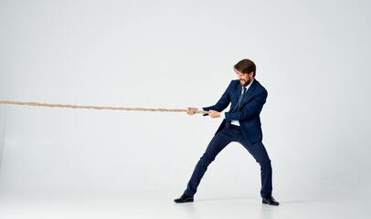 business man in a suit pulls the rope studio light background