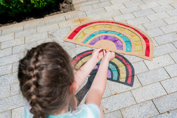 Close-up of child s hand holding a rainbow craft suncatcher. Summer fun activities for the...