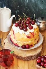 Cherry cake. Yeast bun with cherries and cream. Top view, wooden and blue background.