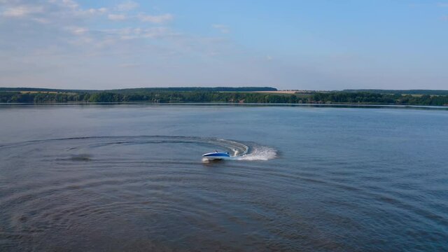 Motorboat on blue water surface. Tourists travel in a high-speed boat in the sea. White foam after the boat sailing on water. Aerial view
